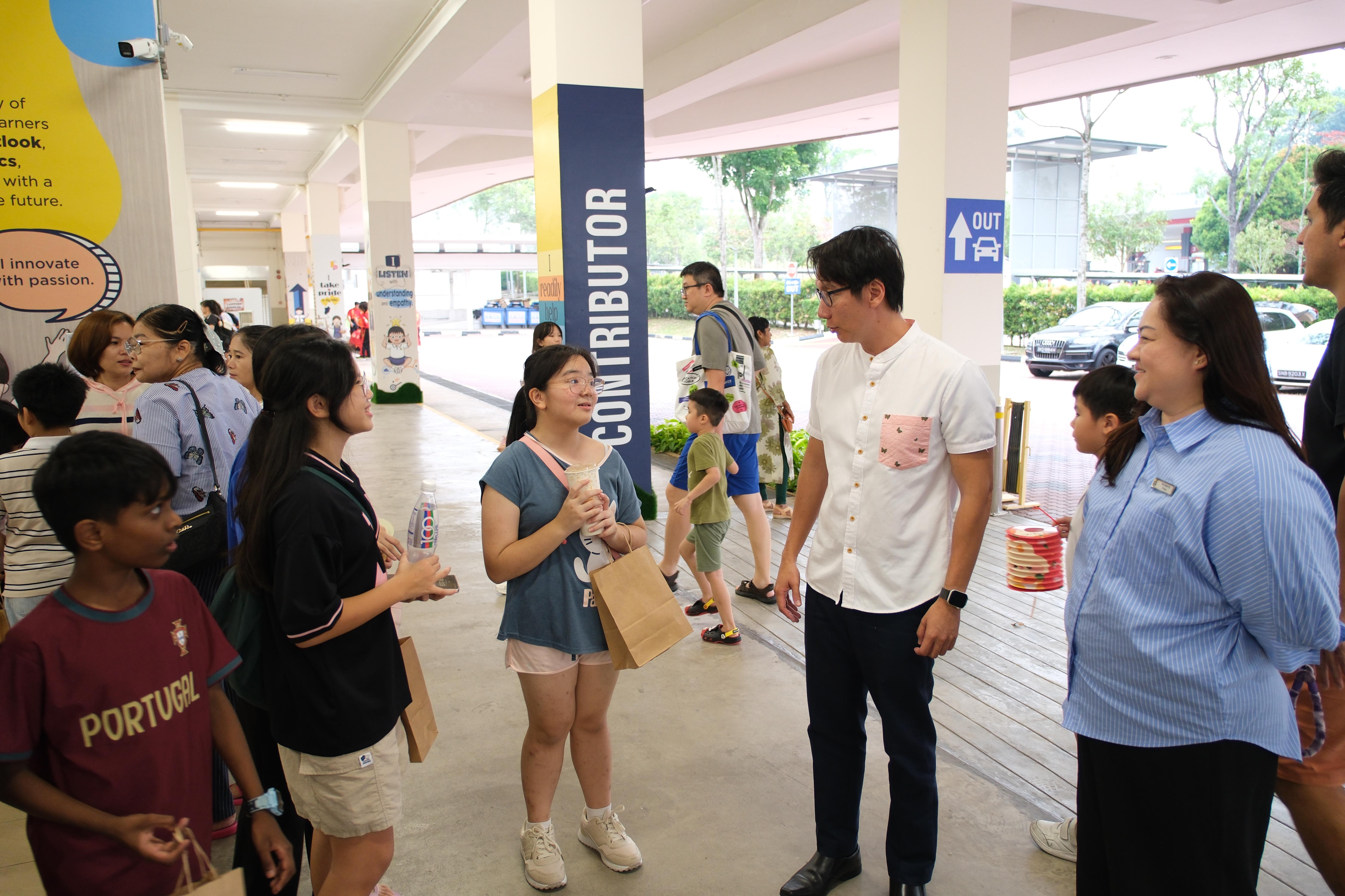 Mr Edward Chia engages in a friendly conversation with families, enjoying the lively atmosphere of Cultural and Family Night.